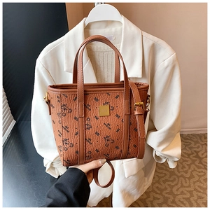 Detail of a brown tote bag featuring bear print, litchi texture, and golden hardware