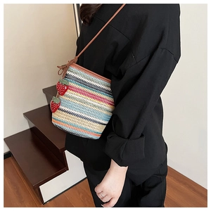 Détail du sac seau tissé avec rayures colorées et pendentif fraise rouge décoratif