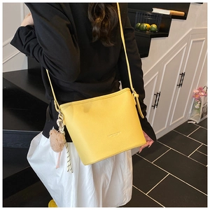 Litchi pattern yellow bucket bag detail with cute brown plush bear charm accessory