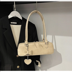 Détail du sac à bandoulière beige à motif crocodile avec pendentif cœur et zip en métal