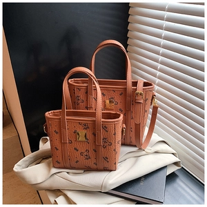 Detail of tan printed tote bag set with bear pattern and gold metal logo plaque
