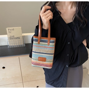 Détail de la texture tissée à rayures colorées et de l'anse en cuir de ce sac seau