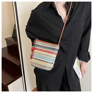 Détail du sac seau tissé coloré avec breloques fraises rouges et bandoulière en cuir