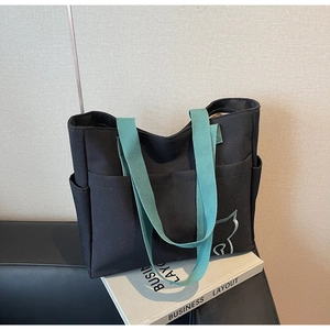 Detail of black canvas tote bag with green straps and silver cat silhouette print