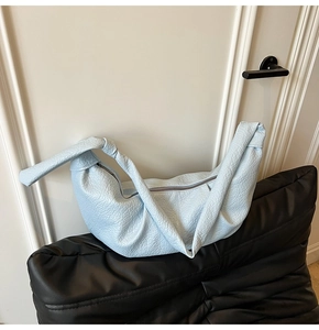 Detail of light blue crescent bag featuring lychee grain leather and knotted strap design