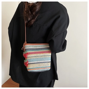 Détail d'un sac bandoulière tissé coloré avec des breloques fraises 3D et une bandoulière