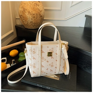 Close-up of a cream tote bag with bear print and gold hardware on a book background