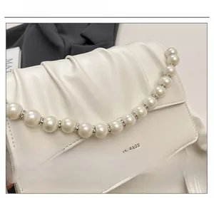 Detailed macro view of white pleated leather texture and elegant pearl chain with rhinestones