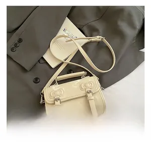 Close-up of cream patent leather mini bag with decorative bows and silver hardware