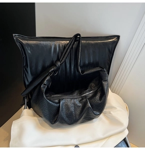 Detail of black pleated hobo bag showing pebbled leather texture and knot strap design