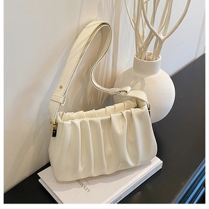 Close-up of pleated cloud bag in cream white with premium leather texture and gold hardware