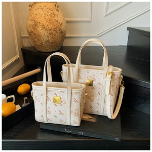 Close-up of cream-colored tote bags with brown bear print and golden MB logo