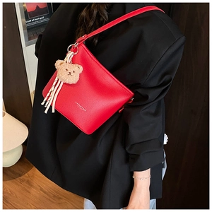 Red pebbled leather bucket bag featuring plush bear charm and silk scarf handle detail
