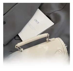 Detail of cream Boston bag with 3D bow and metal buckle on grey blazer backdrop