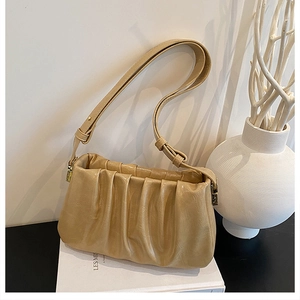 Close-up of beige ruched cloud bag with adjustable strap and premium gold hardware