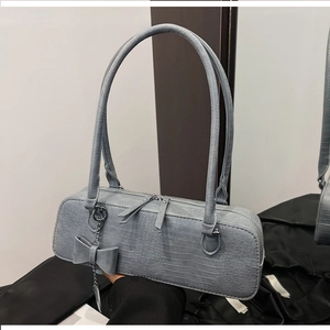 Détail du sac gris à motif crocodile avec double fermeture éclair et nœud décoratif