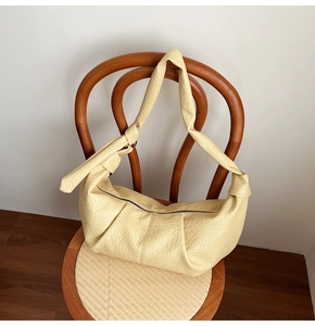 Detail of light yellow lychee grain leather handbag with knot strap and pleated design