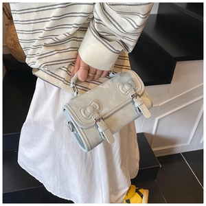 Detail of light blue cylinder bag featuring 3D bows and silver buckles on a staircase