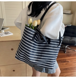 Close-up of a large capacity woven tote bag with black and white stripes for travel