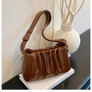 Detailed view of dark brown ruched shoulder bag with oil wax leather texture and gold hardware