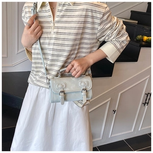 Detailed view of light blue crossbody bag with ribbon bows and faux leather texture