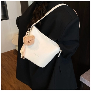 Detailed shot of white lychee leather bucket bag with cute bear and scarf charms