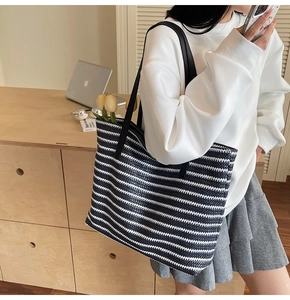Detail of navy striped straw tote bag showing large capacity and leather shoulder straps