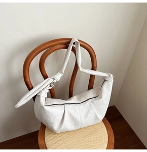 Close-up of white crescent hobo bag with litchi texture hanging on a wooden chair