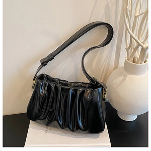 Detail of black pleated cloud bag with shiny leather texture and gold metal hardware