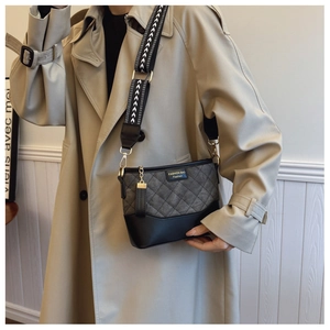 Detail of vintage quilted crossbody bag with arrow pattern strap and gold logo