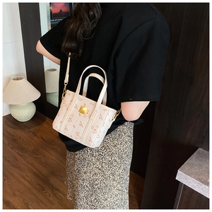 Detail view of stylish cream handbag with bear print pattern and golden logo plate