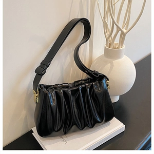 Close-up of black pleated cloud bag with glossy texture and elegant gold hardware