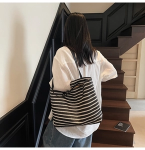 Detail of black and white striped woven tote bag with premium black leather shoulder straps