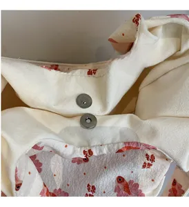 Detailed close-up of the silver magnetic metal clasp on the floral canvas tote bag