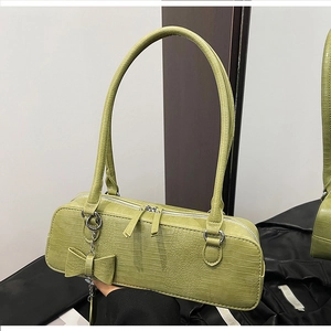Détail du sac à bandoulière vert croco avec double fermeture éclair argentée et nœud décoratif