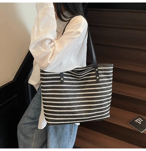 Detail shot of the large woven tote bag featuring black and white stripes with leather straps