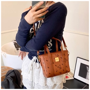 Detail view of a brown leather bucket bag with bear print and golden metal logo plate