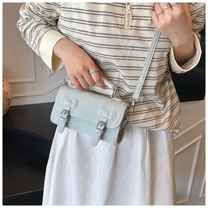 Detail showing mint green crossbody bag with top handle and two decorative bows