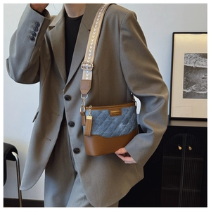 Detail of blue quilted denim and brown leather bucket bag with wide woven strap