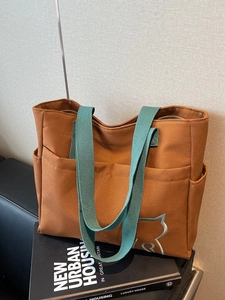 Minimalist canvas tote bag featuring a cat outline and green straps on book decor