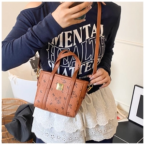 Detail of brown koala print tote bag showing litchi grain texture and gold metal plaque
