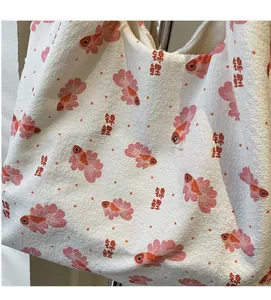Detail of soft wrinkled fabric tote bag with orange koi fish print and floral patterns
