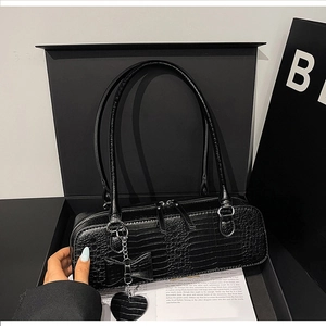 Détail du sac noir texture crocodile avec pendentif nœud dans un coffret cadeau chic