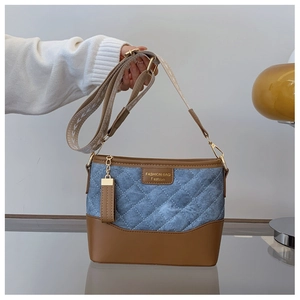 Detail of quilted blue denim and brown leather bucket bag with wide jacquard strap