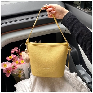 Detail of yellow lychee leather bucket bag with cute bear pendant and top handle
