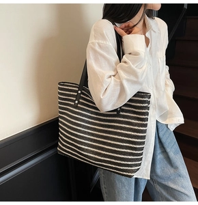 Close-up of black and white striped woven tote bag showing texture and slim shoulder strap