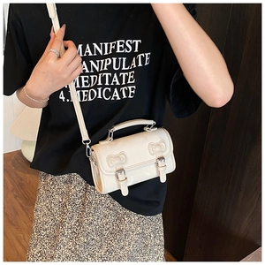 Detail of a vintage cream leather crossbody bag with bow accents and silver buckles