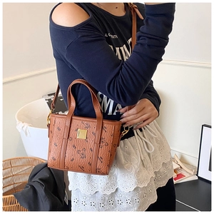 Close-up of brown leather bucket bag with bear patterns and golden metal logo plaque