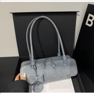 Détail du sac à bandoulière bleu-gris à motif crocodile avec nœud et chaîne en cœur