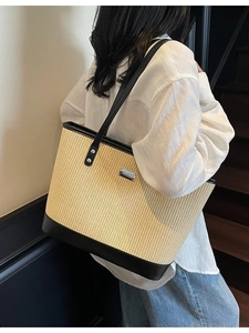 Woven straw tote bag with black leather trim and silver metal logo for summer style
